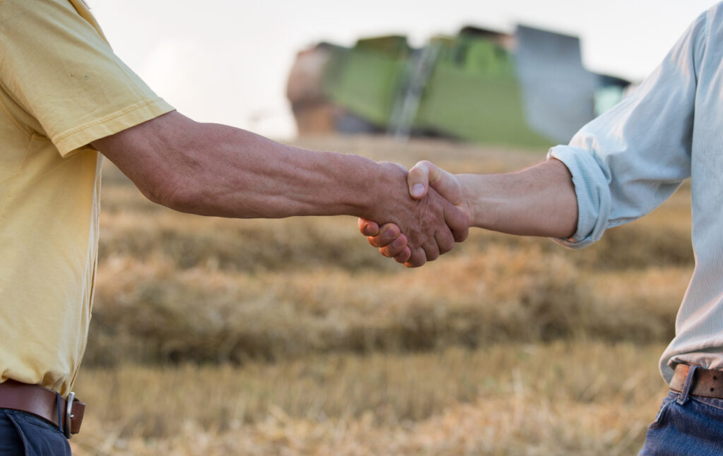 farmers shaking hands in a wheat field